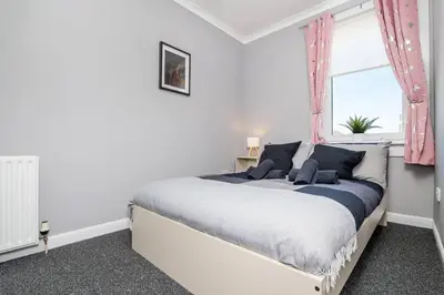 a white bedroom with a large bed with a window at Ideal Work Stays 3BR Free Parking Sleeps 6 in Falkirk