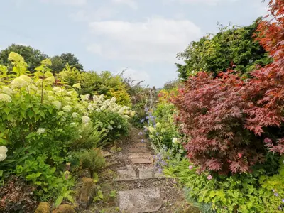 a path through a garden with colorful plants at Balsaggart Farm in Maybole