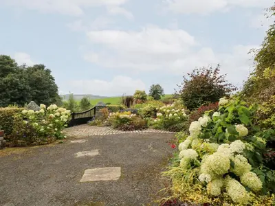 a garden of flowers and plants on a gravel road at Balsaggart Farm in Maybole