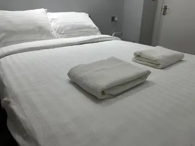 a white bed with two folded towels on it at City Centre Ground floor 3 Bedroom Apartment in Edinburgh