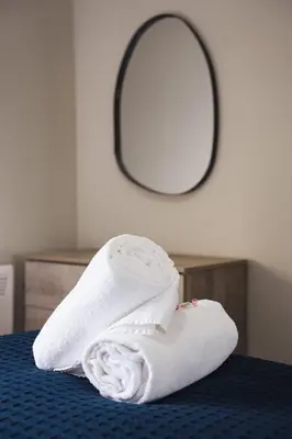 a stack of towels sitting on a bed with a mirror at Coat Apartment in Coatbridge