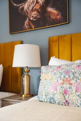 a bed with a pillow and a lamp on a table at Coat Apartment in Coatbridge