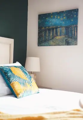 a bedroom with a bed with a painting on the wall at North Elgin Apartment in Clydebank
