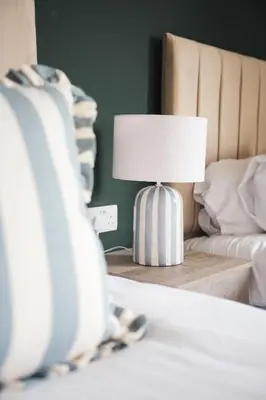 a lamp on a table next to a bed at North Elgin Apartment in Clydebank
