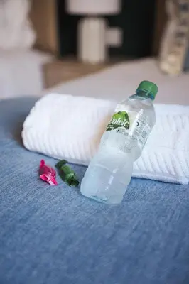 a bottle of water on a bed next to a towel at North Elgin Apartment in Clydebank