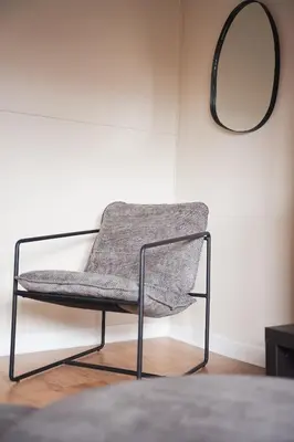 a chair sitting in a room with a mirror at North Elgin Apartment in Clydebank