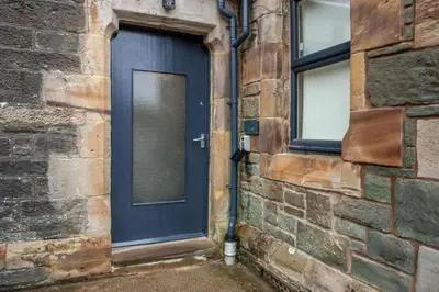 a blue door on the side of a brick building at Stylish 2Bedroom Flat - Central Oban in Oban