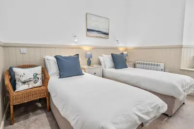 two twin beds in a room with a chair at Elegant 3BD Escape - Perfect Central Location in Oban