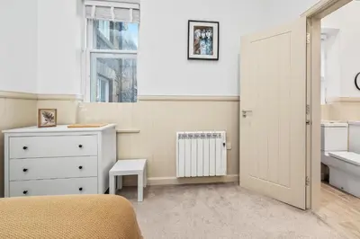 a bedroom with a bed and a sink and a white cabinet at Elegant 3BD Escape - Perfect Central Location in Oban