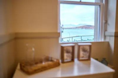 a window with two pictures and a view of the ocean at Luxury 3BD Central Apt with Tower & Seaviews in Oban