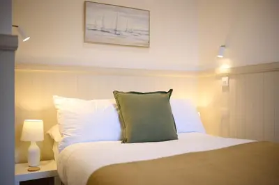 a bed with white pillows and a picture on the wall at Luxury 3BD Central Apt with Tower & Seaviews in Oban