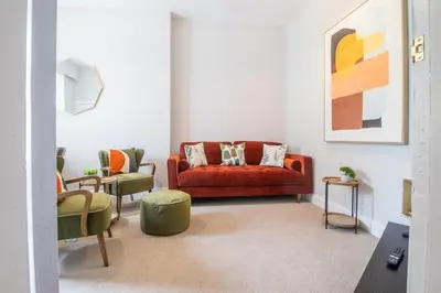 a living room with a red couch and two chairs at Cairnhill House - cosy 3 bedroom in Airdrie