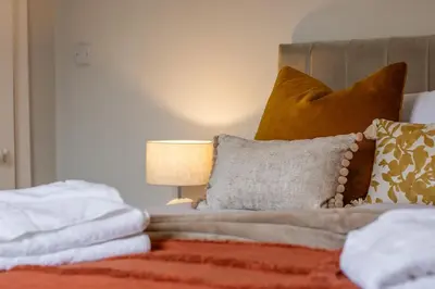 a bed with a bunch of pillows and a lamp at Cairnhill House - cosy 3 bedroom in Airdrie