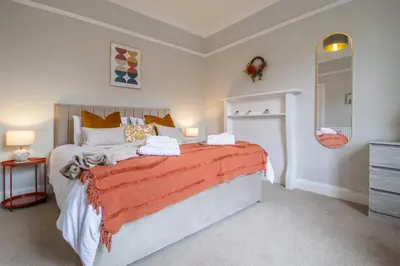 a bedroom with a large bed and a dresser at Cairnhill House - cosy 3 bedroom in Airdrie