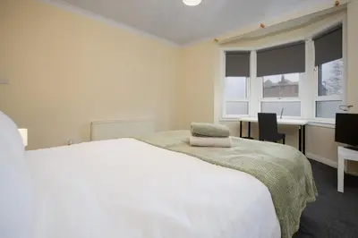 a bedroom with a white bed and a desk and window at Group Stay 3BR Close to Hydro and SECC with Parking in Govan