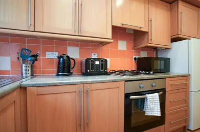 a kitchen with wooden cabinets and a stove top oven at Group Stay 3BR Close to Hydro and SECC with Parking in Govan