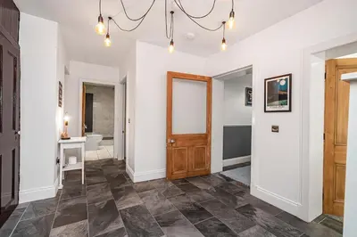 a hallway with a wooden door and a bathroom at The Old Jail - Iconic Views in North Queensferry