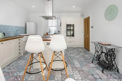 a kitchen with two white stools and a table at The Old Jail - Iconic Views in North Queensferry