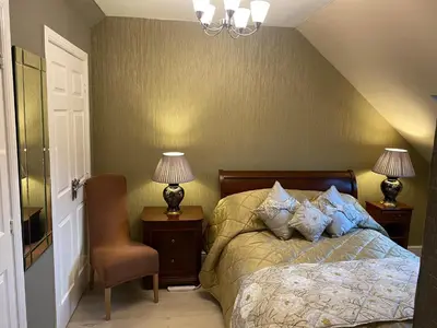 a bedroom with a bed and two lamps and a chair at Doune Duck Ponds Accommodation in Doune