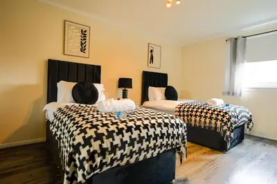 a bedroom with two beds with black and white sheets at 2 BDR Apt At Caledonia Luxe Stays Short Lets & Serviced Accommodation Airdrie in Airdrie
