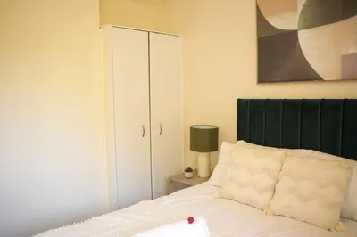 a bedroom with a white bed and a cabinet at 3 BDR House By Caledonia Luxe Stays Short Lets & Serviced Accommodation Wishaw in Wishaw