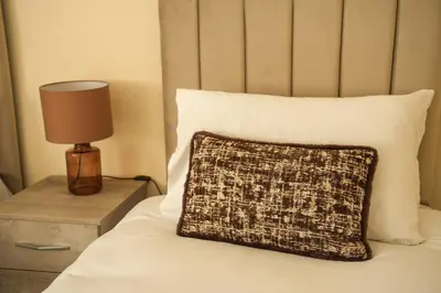 a bed with a pillow and a lamp on a table at 3 BDR House By Caledonia Luxe Stays Short Lets & Serviced Accommodation Wishaw in Wishaw