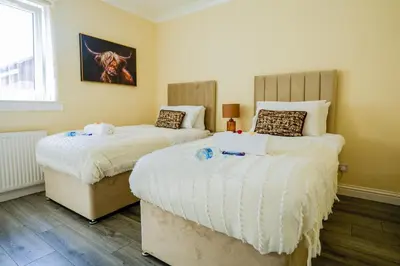 a bedroom with two beds with white sheets and a window at 3 BDR House By Caledonia Luxe Stays Short Lets & Serviced Accommodation Wishaw in Wishaw