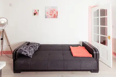 a black bed with an orange pillow on it in a room at Cosy Central Apartment by the Meadows 11 in Edinburgh