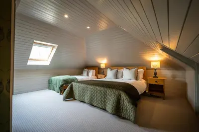 a bedroom with two beds and a window at Buzzard Cottage nestled in a hillside farm in Stirling