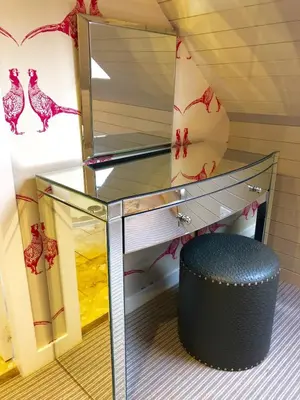 a glass desk with a black ottoman and a mirror at Buzzard Cottage nestled in a hillside farm in Stirling