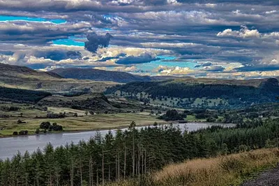 a view of a river in a valley with clouds at Buzzard Cottage nestled in a hillside farm in Stirling