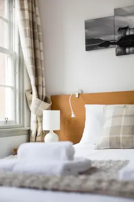 a bedroom with a bed with a lamp and a window at Grassmarket Apartment in Edinburgh