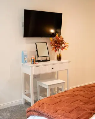 a white desk with a mirror and a vase of flowers at Beechwood in Oban