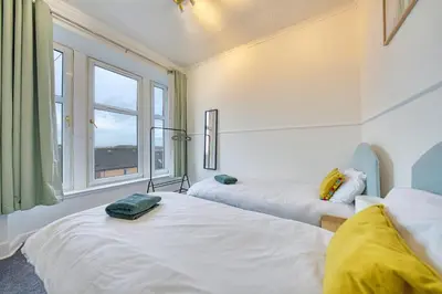 two beds in a room with a window at 3BR Flat Near Maryhill Park and West End with Parking in Partick