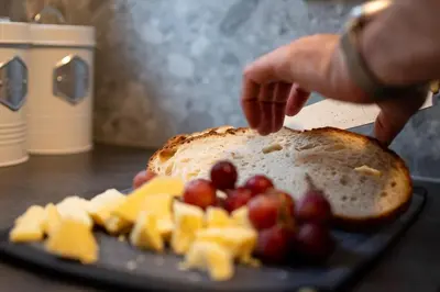 a person is preparing a piece of bread with fruit on a plate at Finnieston 1BR - Walk to Hydro & SEC - Parking in Glasgow