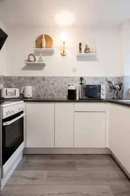 a white kitchen with white cabinets and appliances at Finnieston 1BR - Walk to Hydro & SEC - Parking in Glasgow