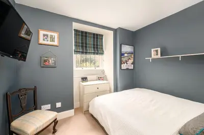 a bedroom with blue walls and a bed and a window at Elegant Flat with Garden in Edinburgh West End in Edinburgh