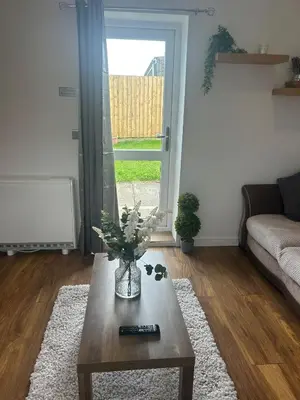 a living room with a vase of flowers on a coffee table at Muirside Cottage in Stirling