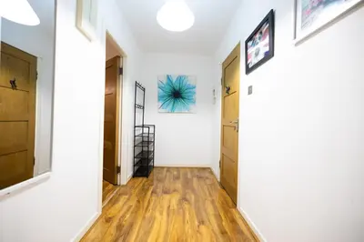 a hallway with white walls and wooden floors at Sauchihall Apartment in Glasgow