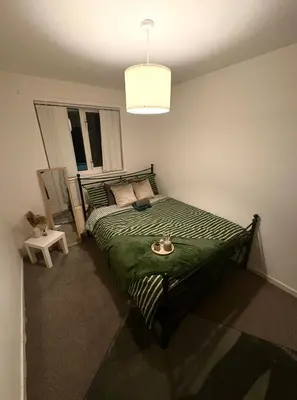 a bedroom with a bed with a green comforter at Tartan Nest- Entire house- Sleeps 8 guests in Mansewood