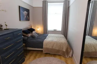 a small bedroom with a bed and a mirror at Cosy 1-Bedroom Flat, Walk to Beaches in Troon