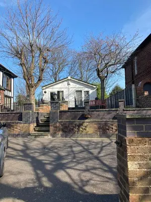 a white house with a fence and stairs in a driveway at Blackpool chalet - free parking in Moffat