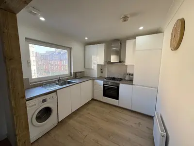 a kitchen with white cabinets and a washer and a window at Luxurious 2BR, 8 mins from centre in Glasgow