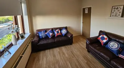 a living room with two leather couches and a window at Silver Tides House in Greenock