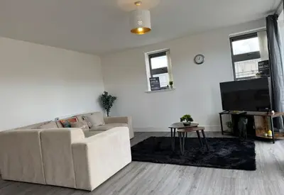 a white living room with a couch and a tv at Buchanan Penthouse in Glasgow