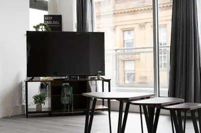 a living room with a tv and two tables and a large window at Buchanan Penthouse in Glasgow