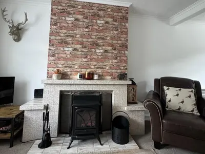 a living room with a brick fireplace and a chair at Tickety-Boo Luss Loch Lomond in Luss