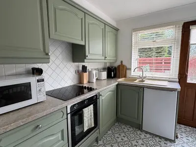 a kitchen with green cabinets and a white microwave at Tickety-Boo Luss Loch Lomond in Luss