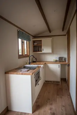 a small kitchen with white cabinets and a sink at Pentland Shepherd Huts in Penicuik