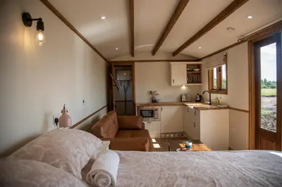 a bedroom with a bed and a kitchen in a house at Pentland Shepherd Huts in Penicuik